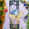Front view of barn owl Jugendstil cross stitch pattern. The piece is large and vertical. The owl moves outside of the boundaries of the window. There are lots of plants surrounding the scene. Colors are mainly black, blue, green, teal, red, beige.