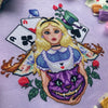 Front, angled view of Alice and Cheshire Cat cross stitch pattern. Cheshire cat head is purple and large, with bared teeth and green eyes. Alice is surrounded by objects like cards, a hat, teacups, roses and a mushroom.
