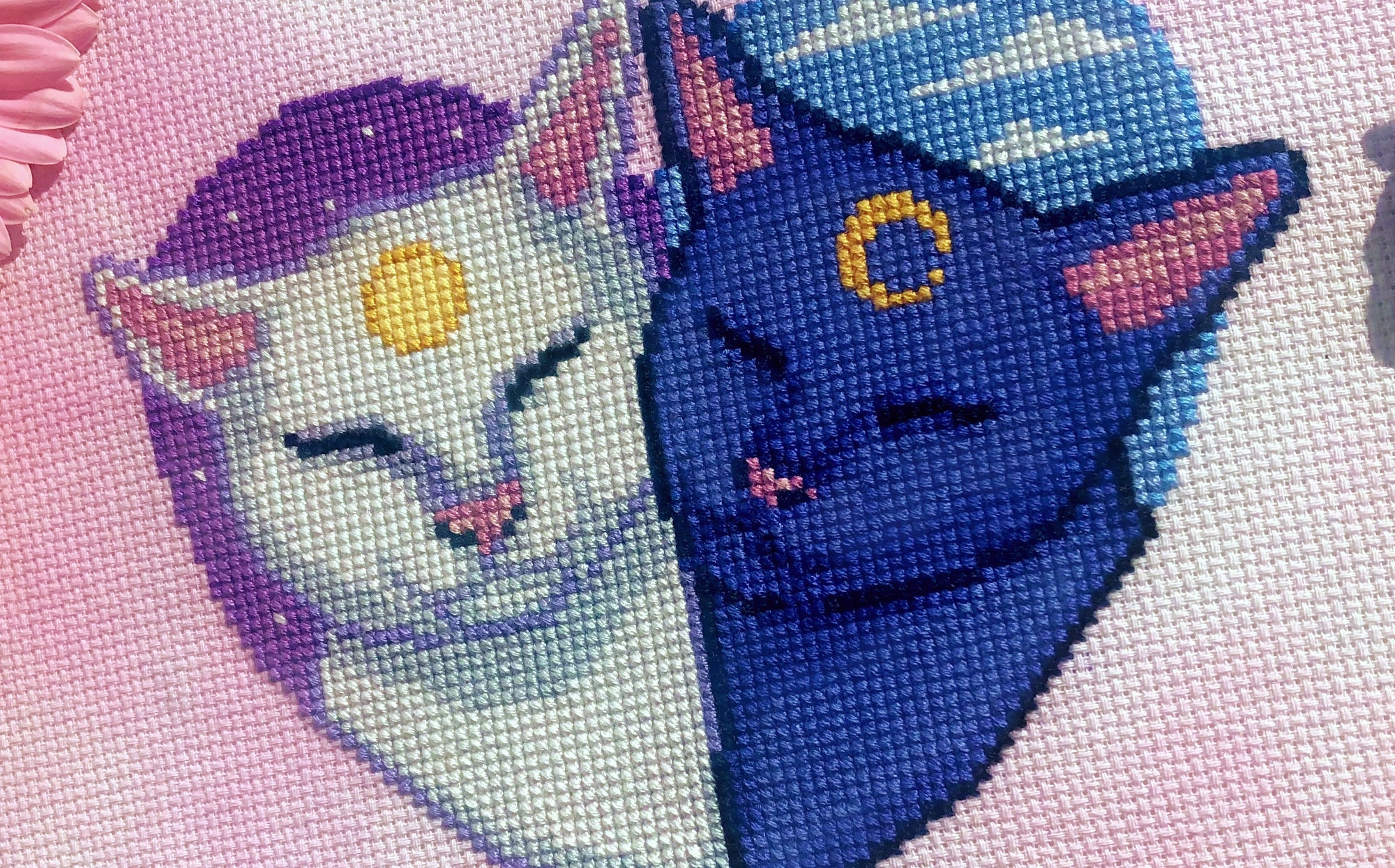 Slightly zoomed in view of Smitten Kittens. The cat on the left is white with a sun on his forehead, the cat on the left is blue with a moon on his forehead. Their noses and earsare bright pink. The scene contains a lot of soft, vibrant colors.