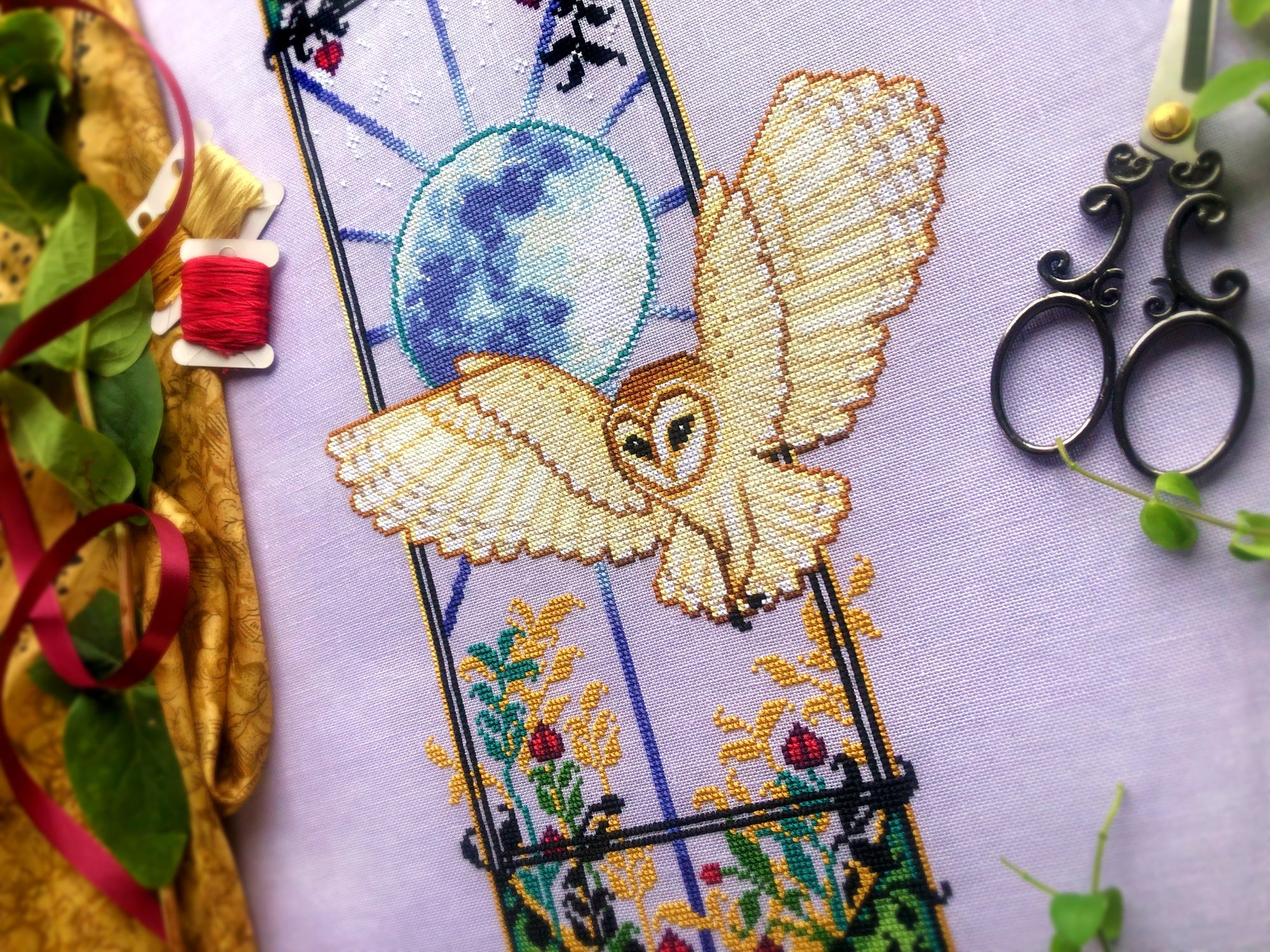 Closeup of barn owl, righthand side. Owl is white and beige, with brown, black and grey details. The wings are clearly defined with visible feathers. Its face is distinct. Behind it is an enormous moon with clear moon landscape detailing.