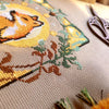 Close-up of Art Nouveau Fox cross stitch pattern. Individual stitches visible. Embroidery scissors in the background. Texture of the fabric is visible too - this is 16ct Aida by Permin of Copenhagen.