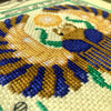 Closeup of Egyptian scarab cross stitch pattern. Angled view of the bottom left. Stitches are tidy. Colors are bright and beautiful.